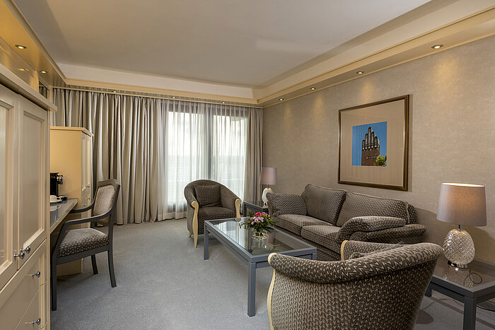 Suite elegante en el Hotel Maritim Darmstadt con sala de estar espaciosa y muebles elegantes.