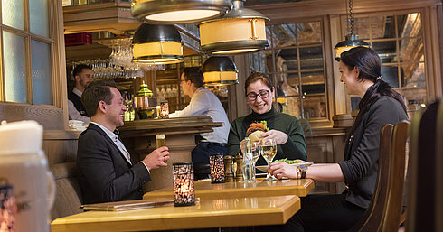 Clientes disfrutando de una comida y bebidas en el ambiente acogedor de la taberna "Kölsche Stuff".