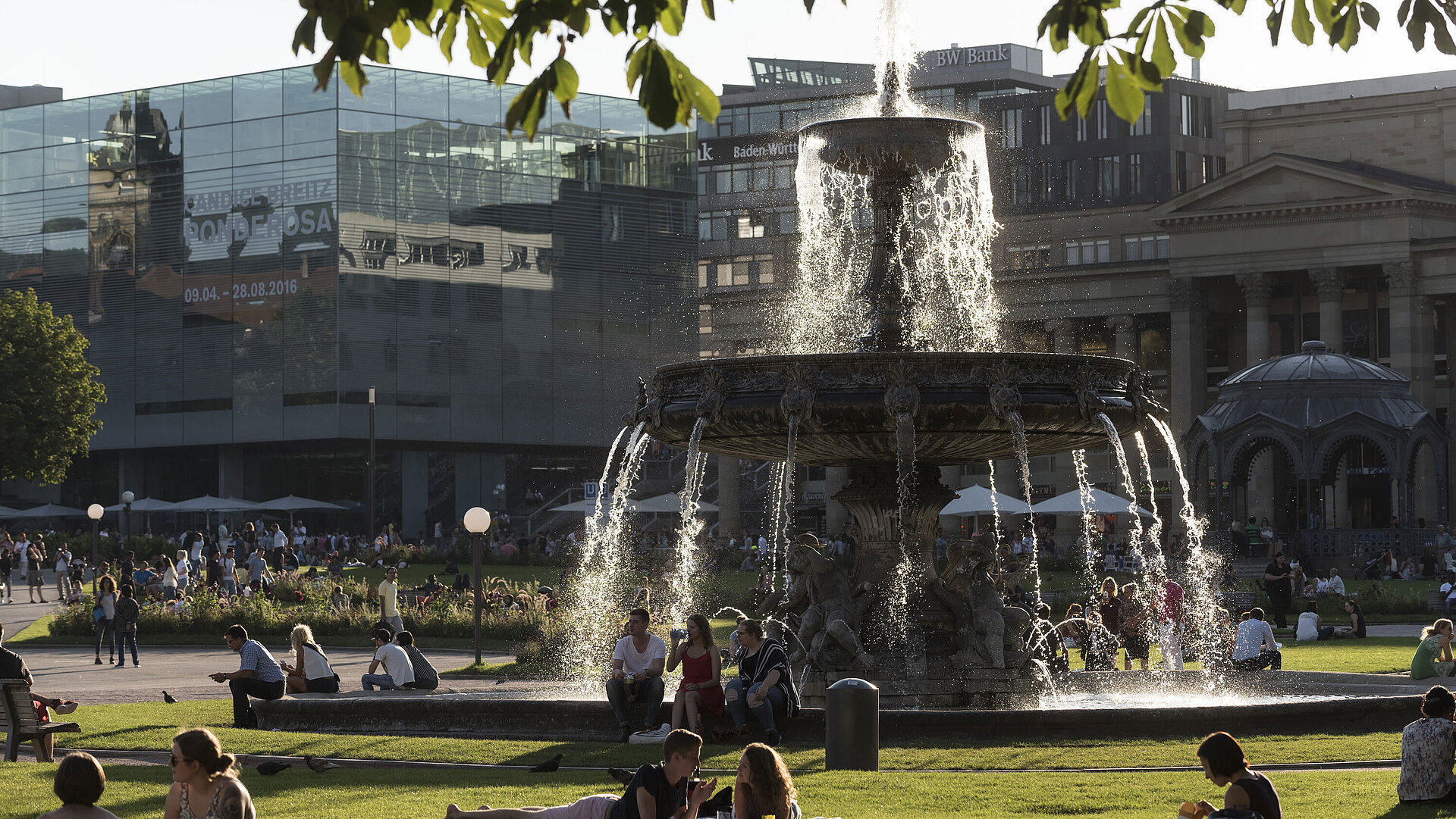 People enjoying the evening sun by the fountain at the lively Schlossplatz in Stuttgart