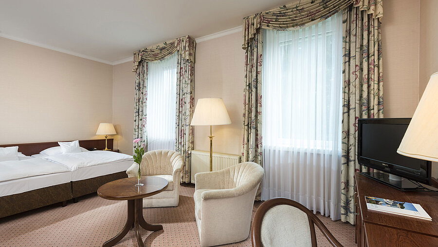 Spacious double room with two windows and seating area at Maritim Hotel Bad Wildungen