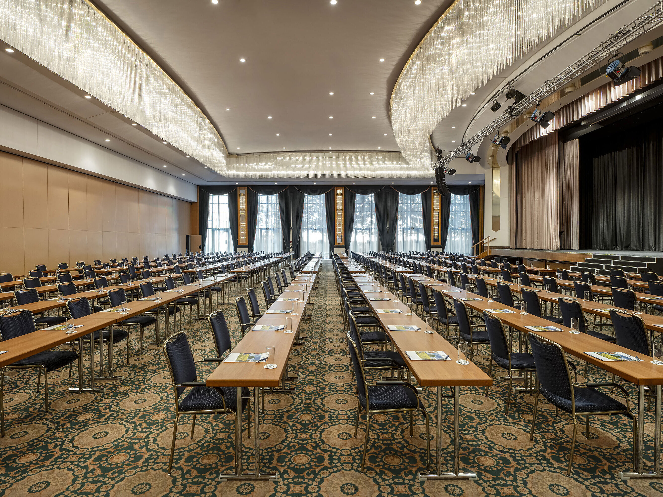 Magnificent hall at the Maritim Hotel Magdeburg with a stage, row seating, and luxurious chandelier.