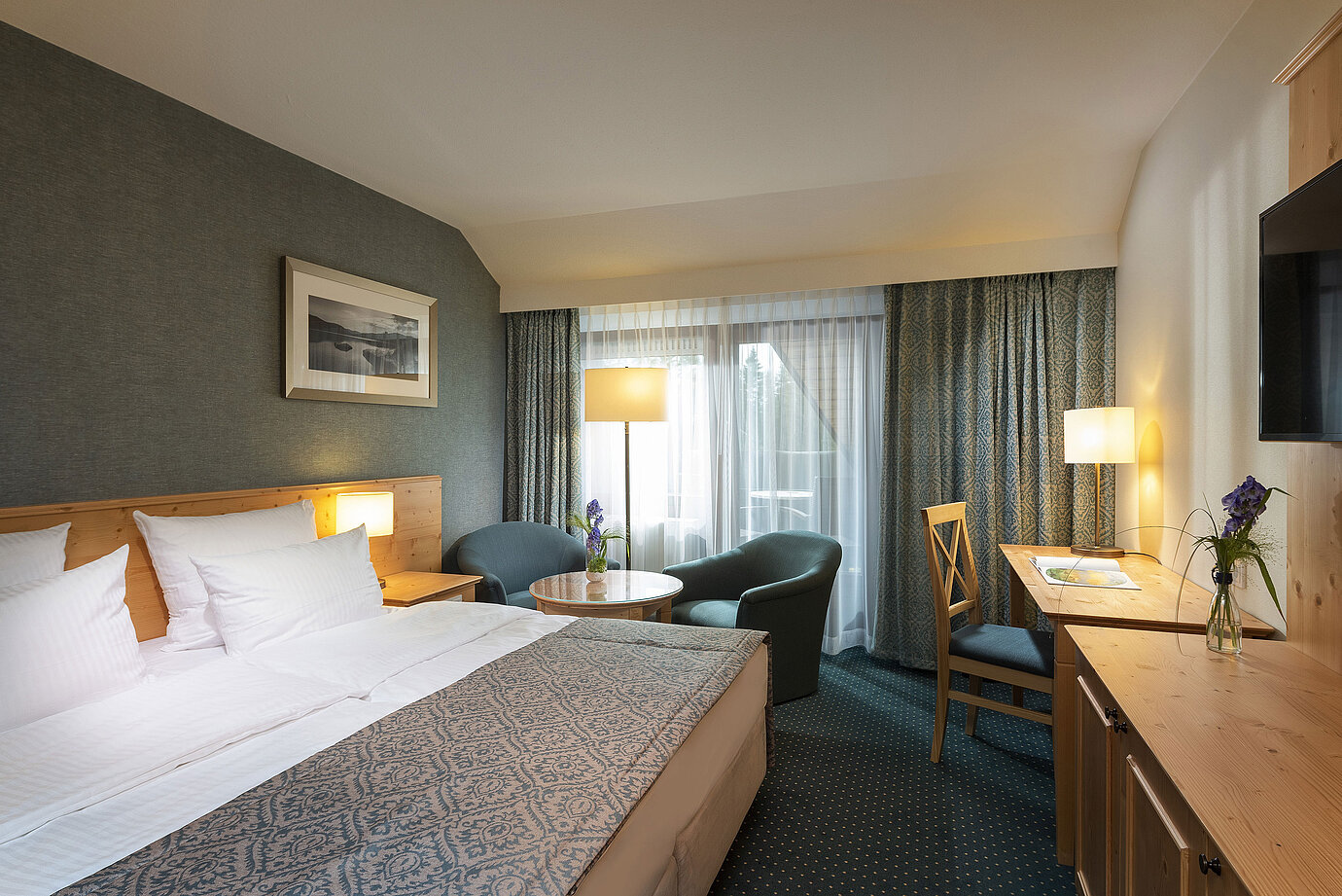 Camera doppia accogliente con scrivania e area salotto al Maritim Hotel Titisee