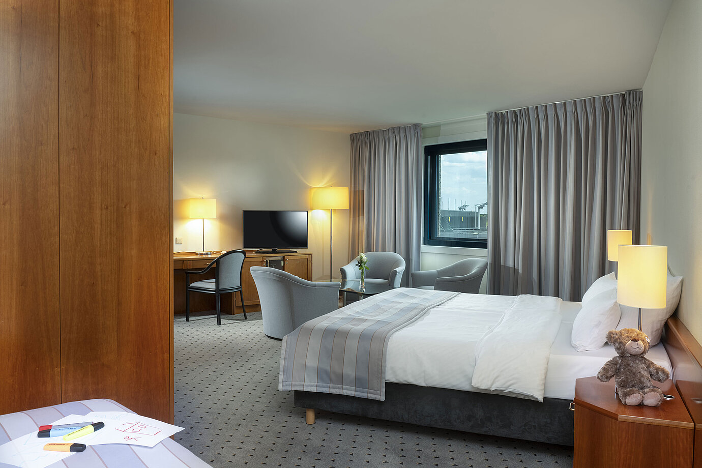 Habitación familiar espaciosa con cama doble, zona de estar y vista al aeropuerto en el Maritim Hotel Hannover.