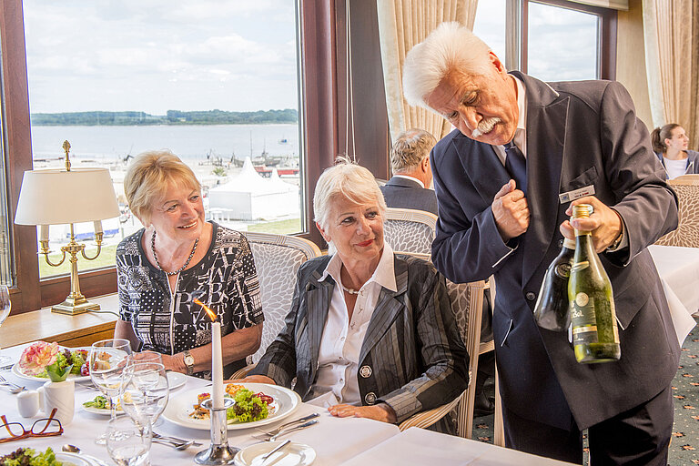 Camarero presenta vinos a los comensales en el restaurante del Maritim Hotel Travemünde.