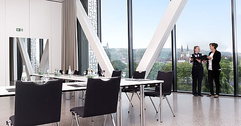 Sala de reuniones moderna del Maritim Hotel Würzburg con ventana panorámica y dos personas hablando