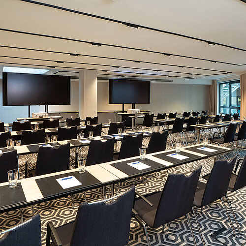 Meeting room 1 with classroom-style seating, conference tables, modern media technology and bright interior.