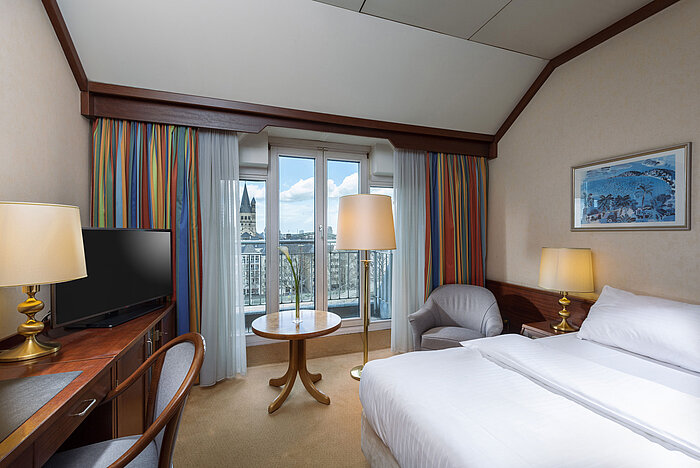 Classic room at Maritim Hotel Cologne with a double bed, desk, and view of the Rhine and historic city center.