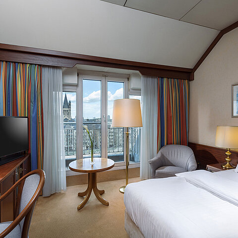 Classic room at Maritim Hotel Cologne with a double bed, desk, and view of the Rhine and historic city center.