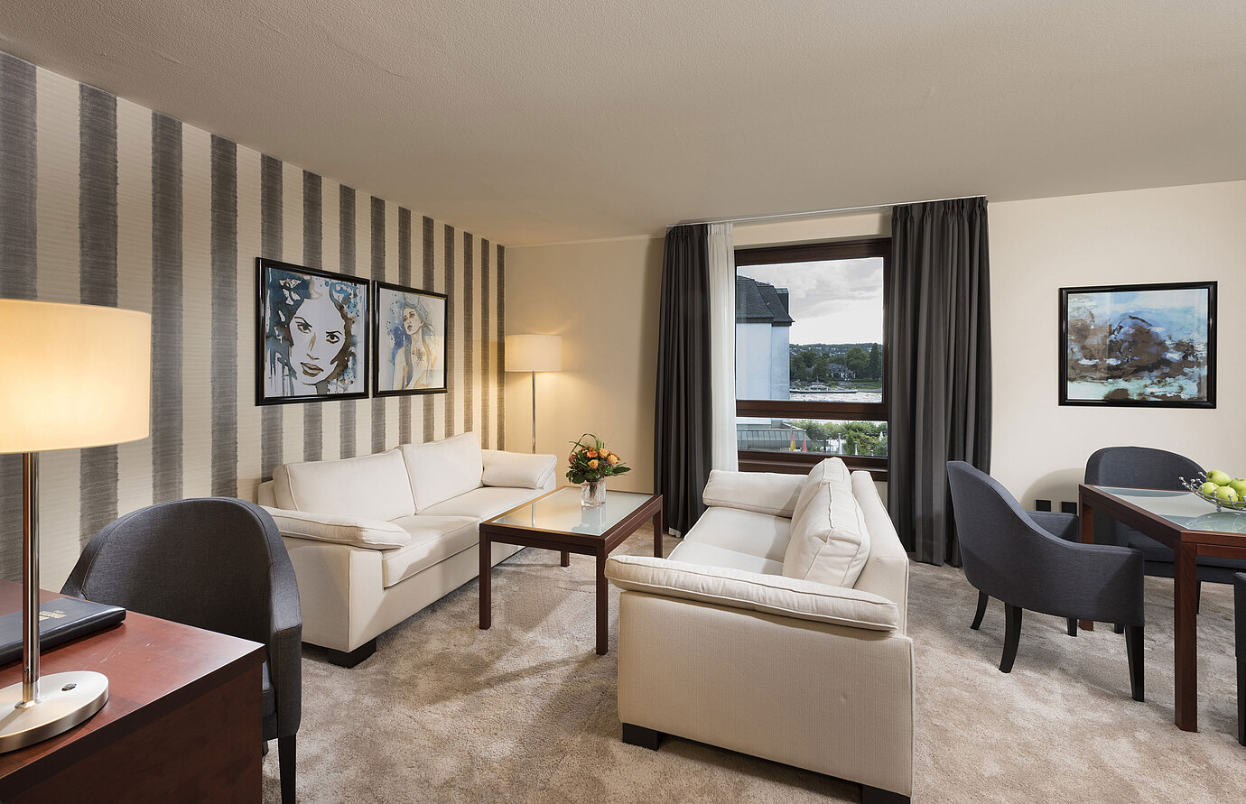 Suite espaciosa con sofás elegantes, mesa de comedor y vista panorámica al Rin en el Maritim Hotel Königswinter.