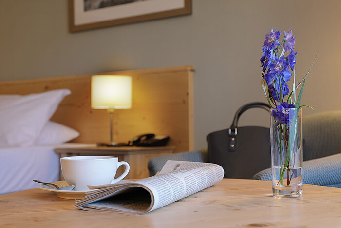 Caffè, giornale e fiore sul tavolo in camera all’hotel Maritim Titisee