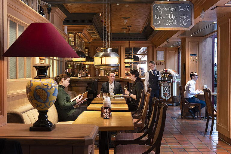 Clientes en la taberna "Kölsche Stuff" disfrutan de un ambiente acogedor y decoración rústica.