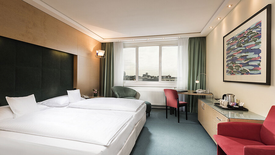 Camera Comfort al Maritim proArte Hotel Berlin con letto matrimoniale, scrivania, poltrona e vista sulla città.