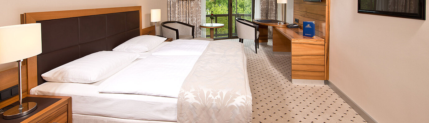 Habitación Comfort  Habitación luminosa en el Hotel Maritim Bad Homburg con cama acogedora, escritorio y balcón con vistas verdes.