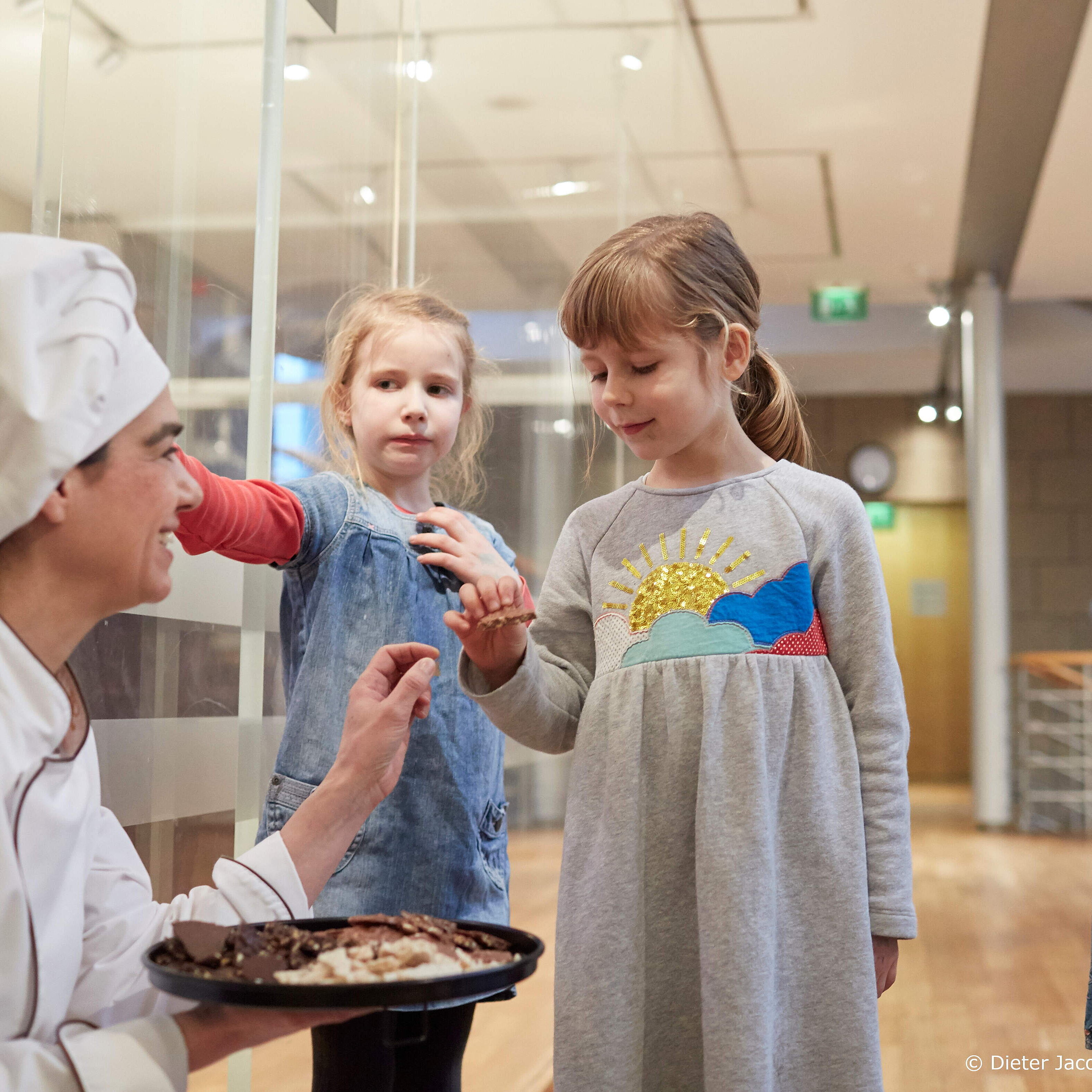 Children tasting sweets with baker or pastry chef