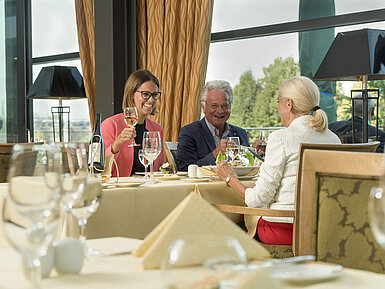 Happy guests enjoying a glass of wine and a meal at the restaurant of Maritim Hotel Dresden.