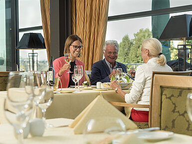 Happy guests enjoying a glass of wine and a meal at the restaurant of Maritim Hotel Dresden.