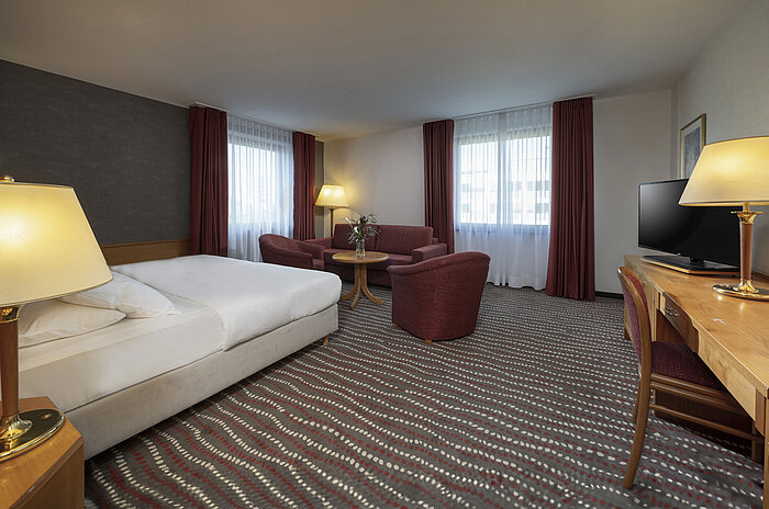 Modern studio room at the Maritim Hotel Magdeburg with a cozy seating area and double bed for a relaxing stay.