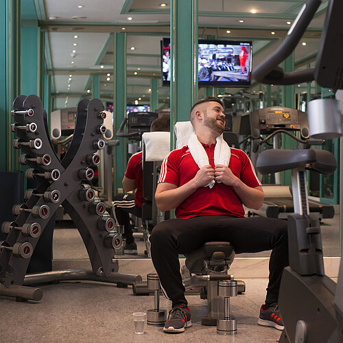 Huésped entrenando en el gimnasio del Maritim Hotel Stuttgart con pesas y máquinas