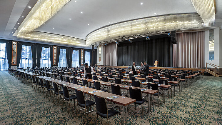 ala magnifica al Maritim Hotel Magdeburg con palco, sedie in fila e lussuoso lampadario.