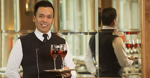 Serveur avec deux verres de vin rosé sur plateau au Maritim Hotel Stuttgart, souriant et professionnel