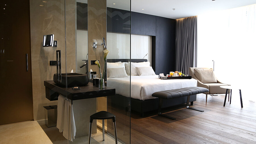 Bright room with double bed, glass-walled designer bathroom and seating area at Maritim Hotel Plaza Tirana