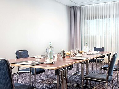 Sala de conferencias moderna en el Hotel Maritim Darmstadt con mesa preparada, luz natural y set de pausa para café.