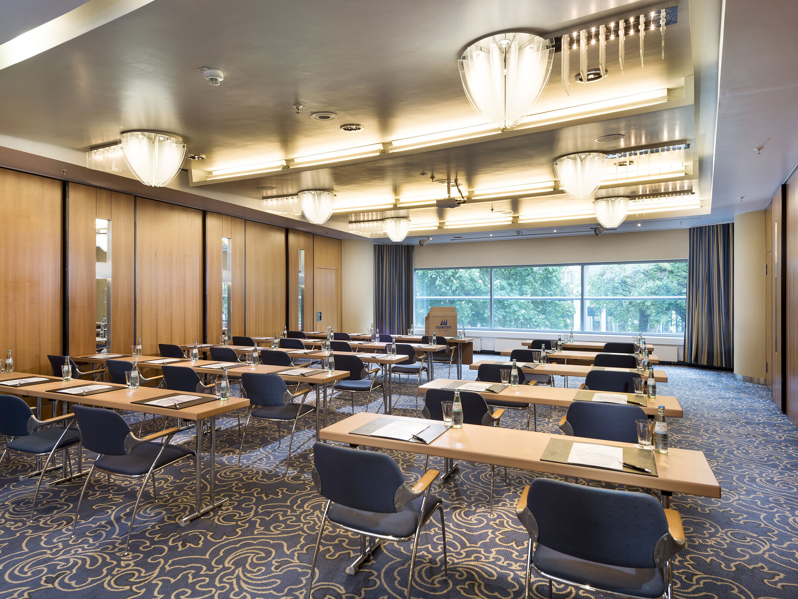 Sala de conferencias luminosa en el Maritim Hotel Frankfurt con sillas en fila, equipamiento moderno y vistas al verde.