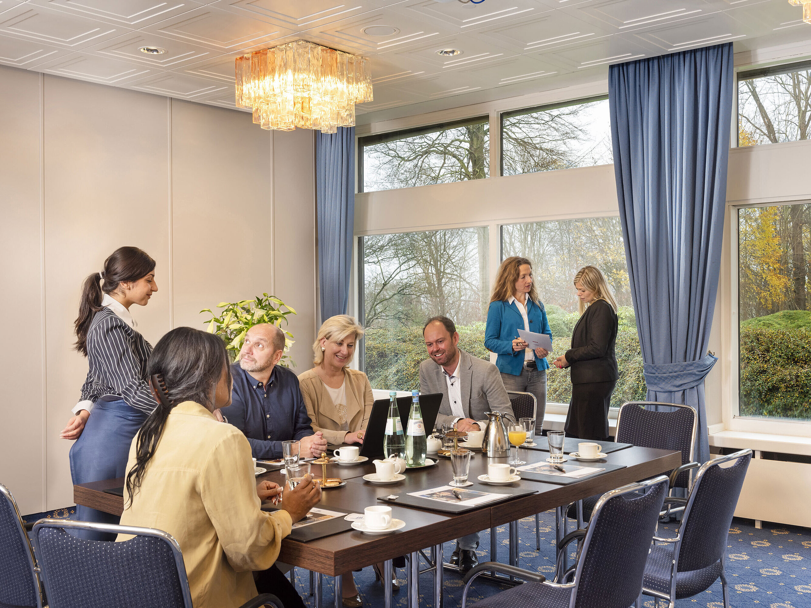 Salón Flensburg en el Maritim Hotel Kiel, un grupo de personas en una reunión, servicio amable y grandes ventanales.