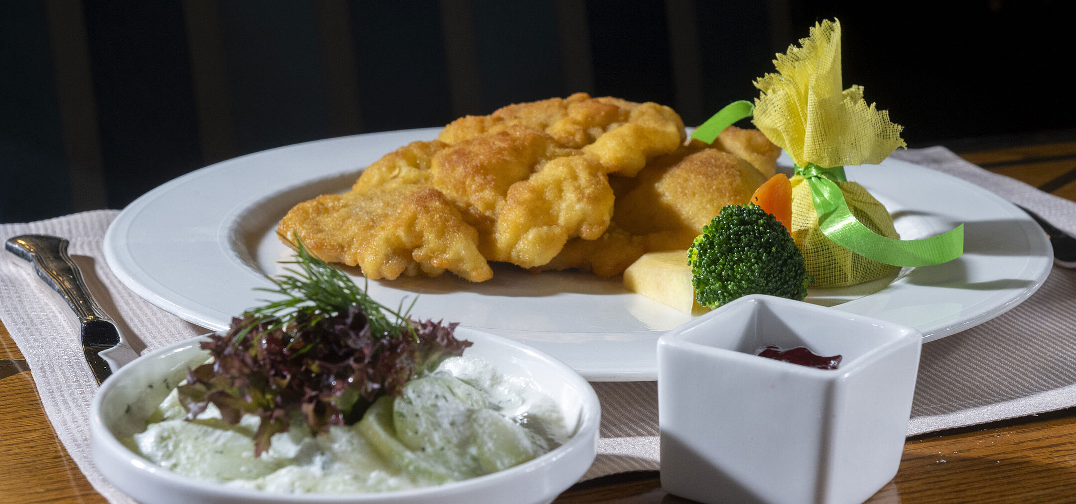 Wiener schnitzel with classic side dishes Crispy Wiener schnitzel with cucumber salad, cranberries and vegetables served on an elegantly presented plate