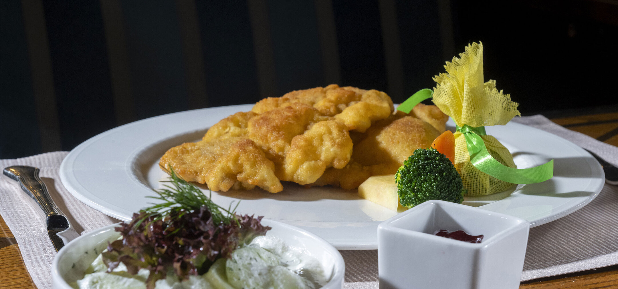 Wiener schnitzel with classic side dishes Crispy Wiener schnitzel with cucumber salad, cranberries and vegetables served on an elegantly presented plate