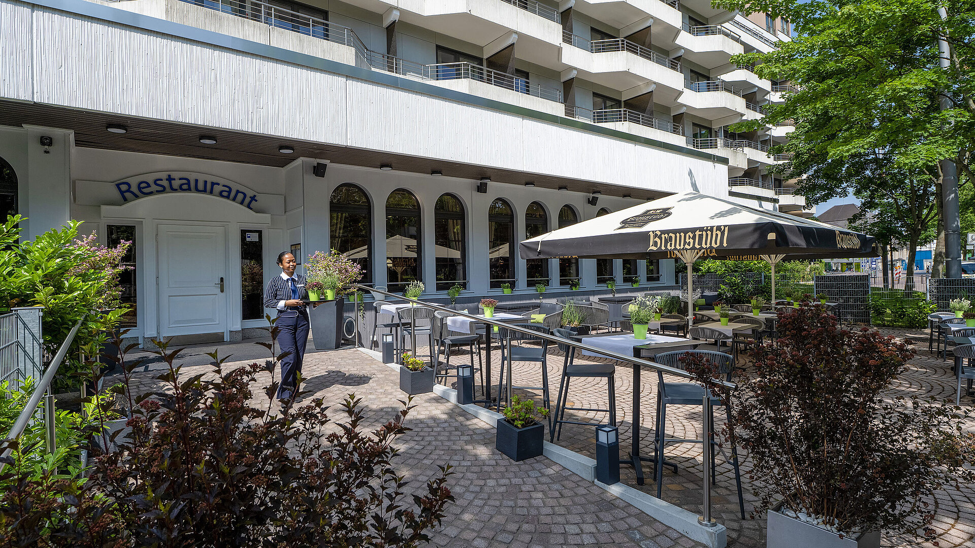 Summer restaurant terrace of the Maritim Hotel Darmstadt with exterior facade and tables under a parasol