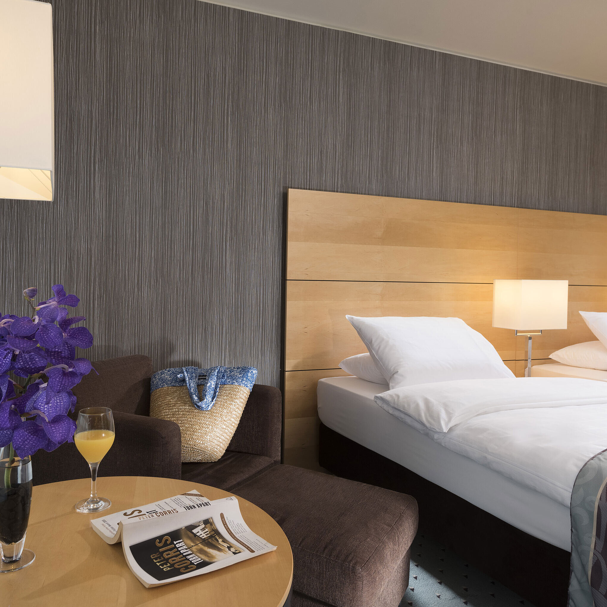 Habitación Classic en el Maritim Düsseldorf con cama doble elegante,zona de estar acogedora,flor fresca y material de lectura