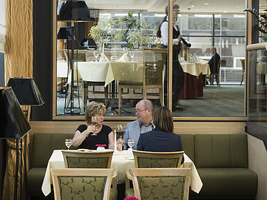 Guests enjoying a glass of wine in a cozy atmosphere at the restaurant of Maritim Hotel Dresden.