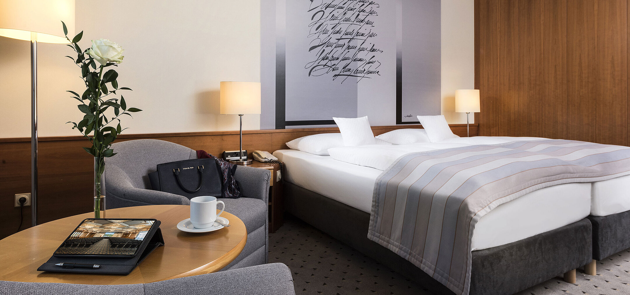 Habitación doble Classic elegante con diseño de pared sofisticado, cama doble acogedora y zona de estar en el hotel Maritim Hannover.