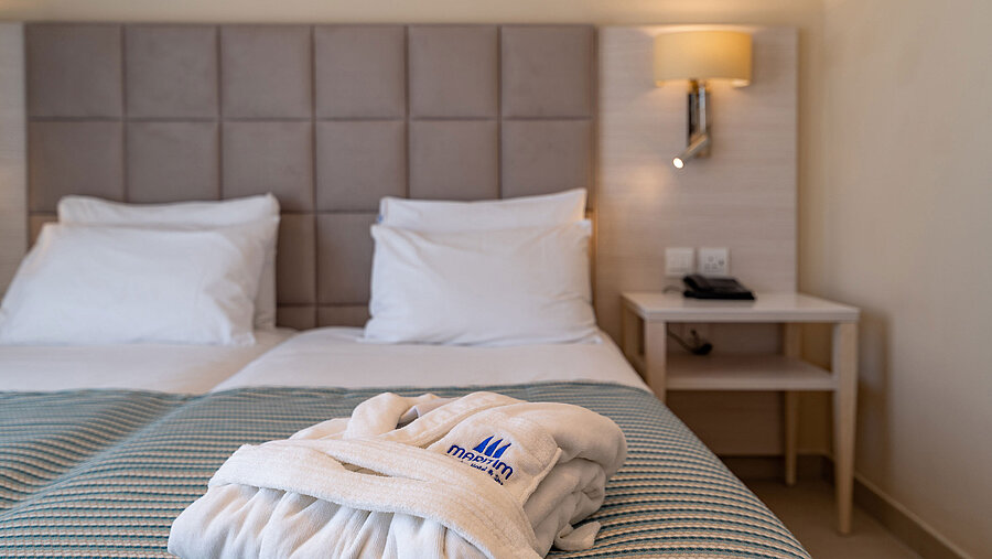 Dettaglio di un letto d’hotel con accappatoio e biancheria morbida