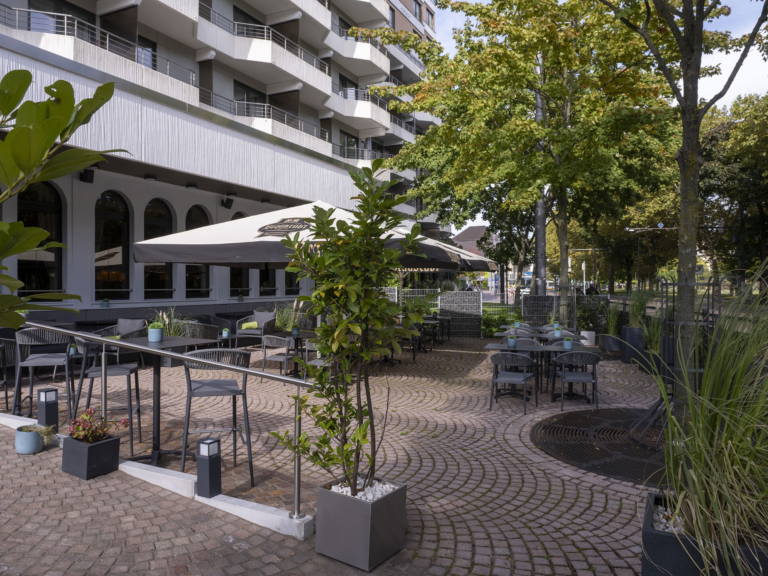 Sunny terrace with modern seating and green plants in front of the Maritim Hotel Darmstadt.