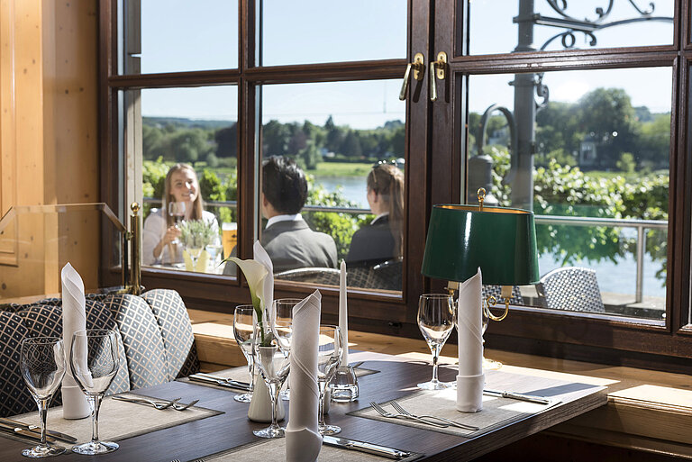 Table élégamment dressée au restaurant du Maritim Hotel Königswinter avec vue sur le Rhin et la nature.