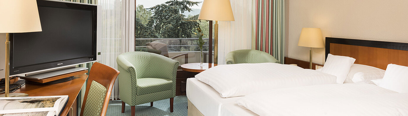 Habitación luminosa en el Maritim Hotel Bad Salzuflen con cama doble, zona de estar y acceso al balcón