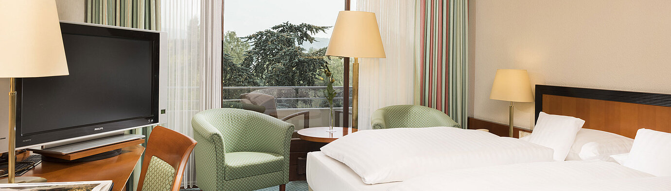 Habitación luminosa en el Maritim Hotel Bad Salzuflen con cama doble, zona de estar y acceso al balcón