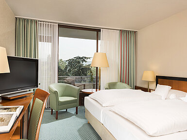 Bright hotel room at Maritim Hotel Bad Salzuflen with double bed, seating area and balcony access