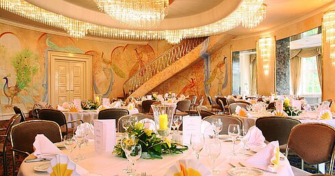 Sala de banquetes elegante con murales, lámparas y mesas decoradas