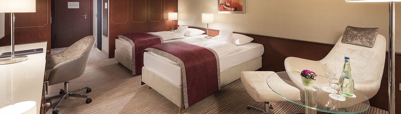 Habitación comfort en el Maritim Hotel Bonn, con dos camas individuales, sillón, escritorio e iluminación moderna.