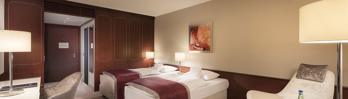 Habitación comfort en el Maritim Hotel Bonn, con dos camas individuales, sillón, escritorio e iluminación moderna.