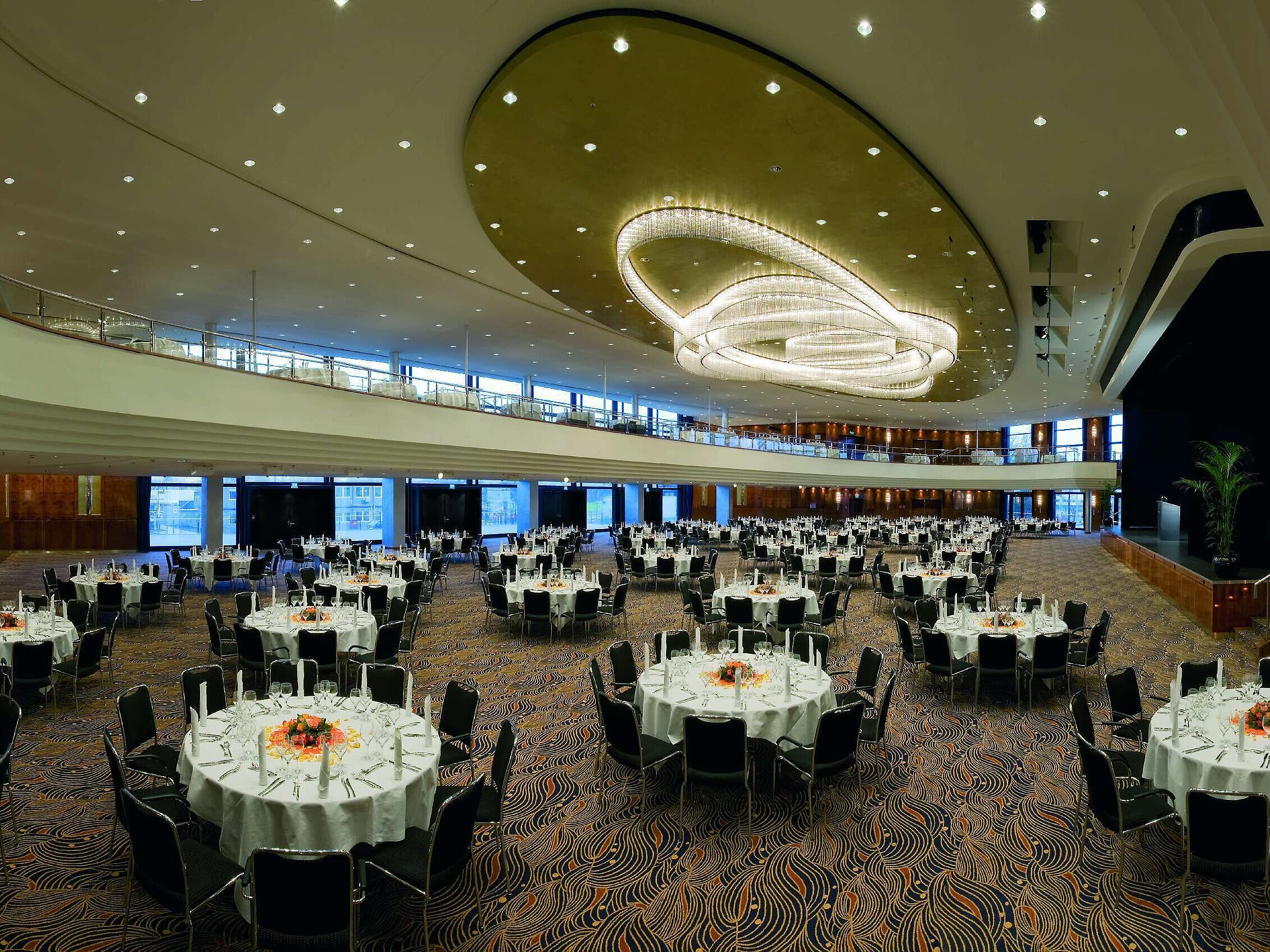 Elegante salón de eventos en el Maritim Hotel Düsseldorf, decorado festivamente con mesas redondas e iluminación impresionante.