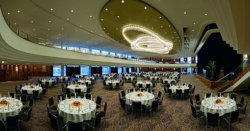 Elegante salón de eventos en el Maritim Hotel Düsseldorf, decorado festivamente con mesas redondas e iluminación impresionante.