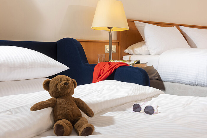 Chambre familiale confortable du Maritim Hotel Frankfurt avec ours en peluche, lunettes de soleil et lits douillets.