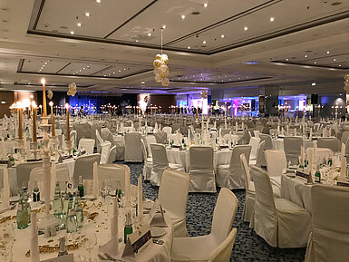 Festively decorated tables with candles and decor for a New Year's Eve party in the large banquet hall of Maritim Berlin.