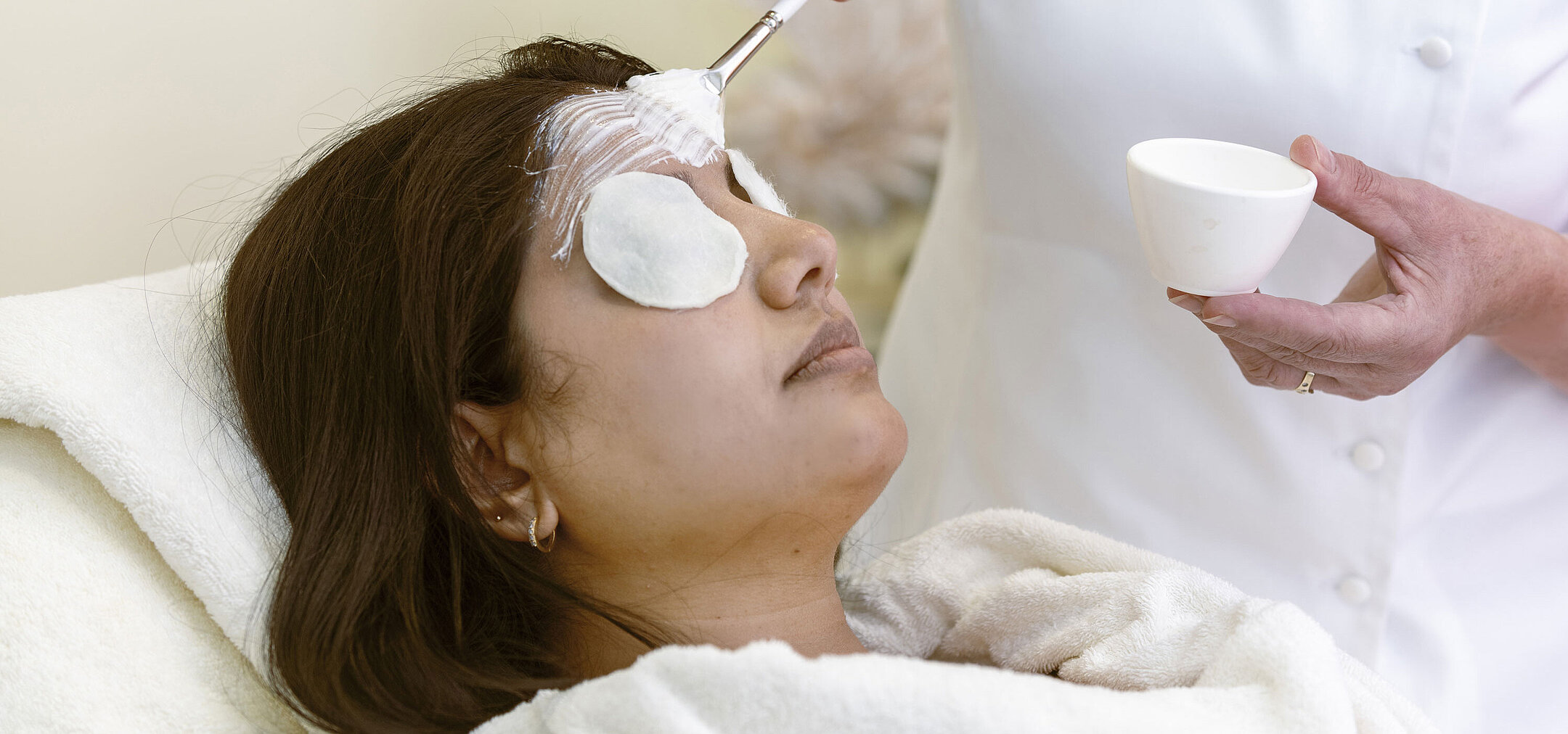 Facial treatment at the Maritim Hotel Spa: A woman receives a face mask and relaxing care with cotton pads.