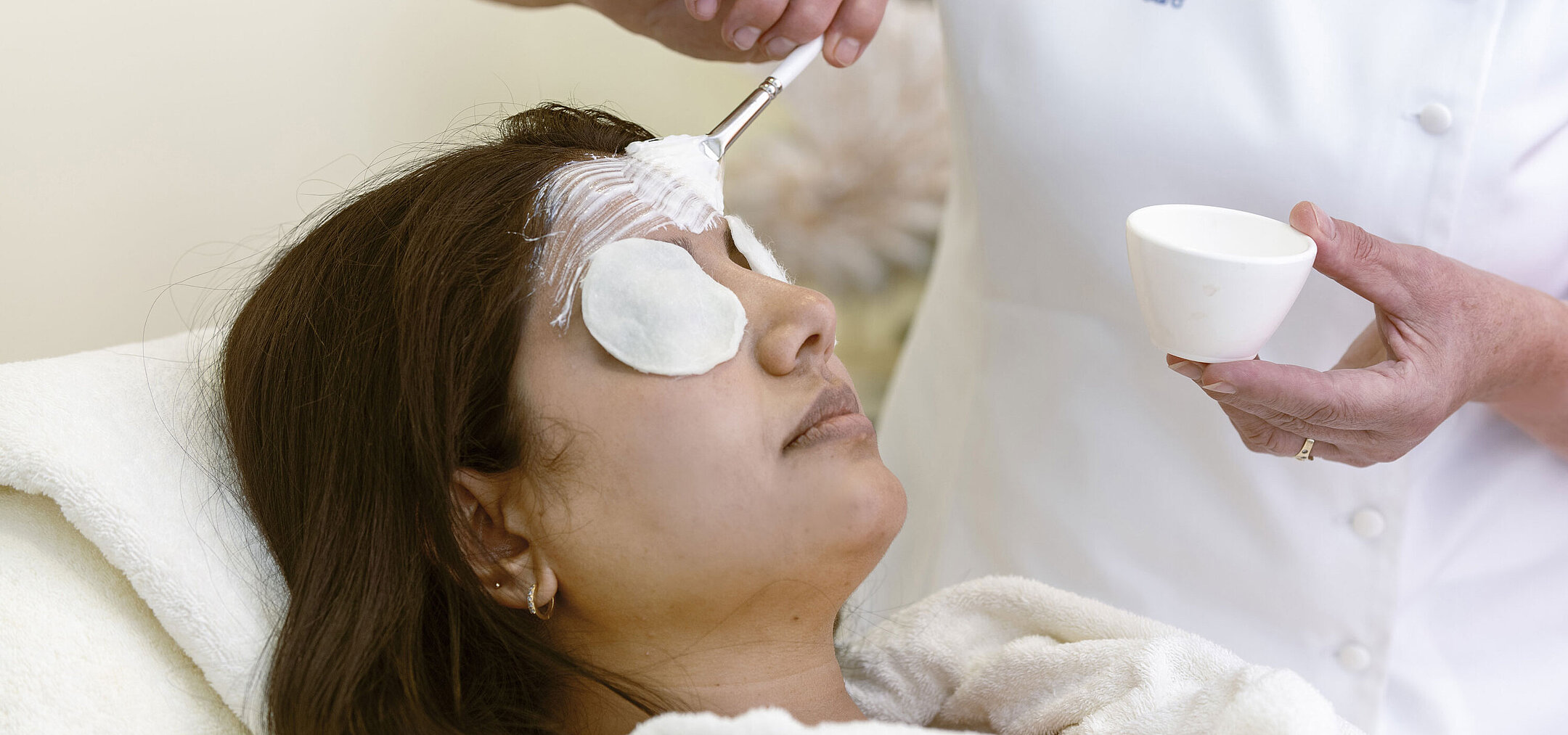 Trattamento viso alla Spa dell'Hotel Maritim: Una donna riceve una maschera e cura rilassante con dischetti di cotone