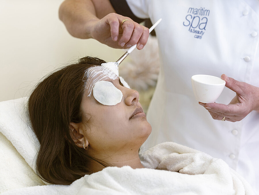 Trattamento viso alla Spa dell'Hotel Maritim: Una donna riceve una maschera e cura rilassante con dischetti di cotone